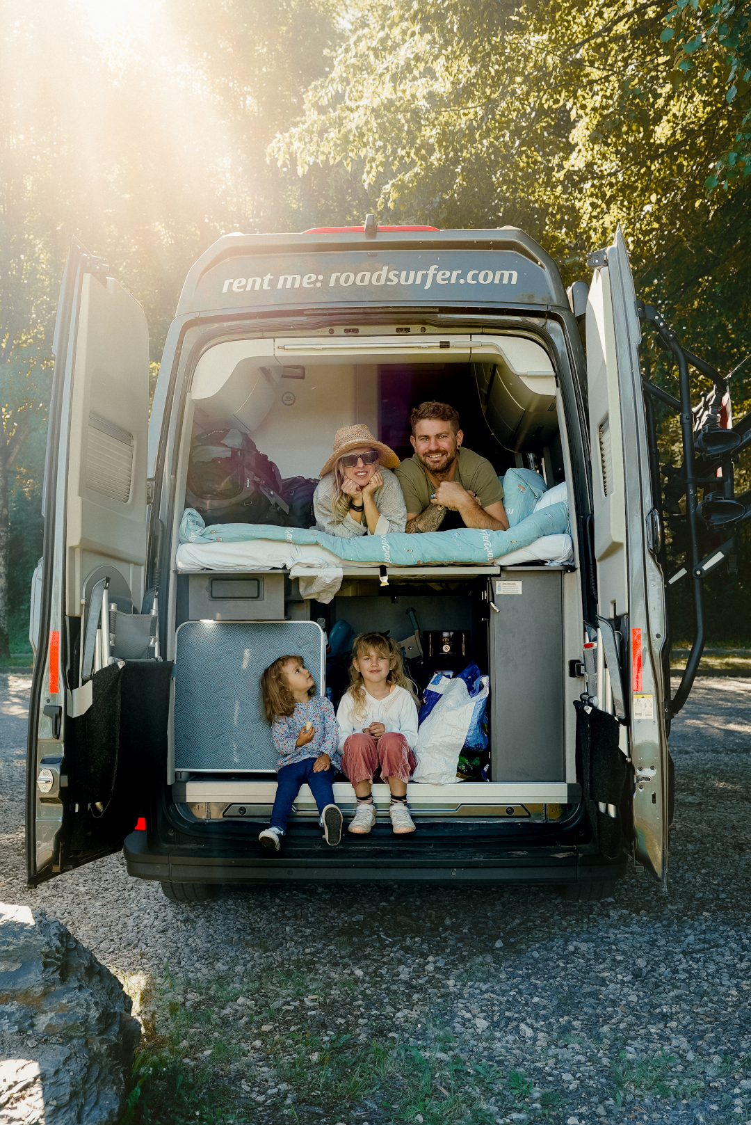 Familie schaut aus der Rückklappe eines roadsurfer Camper Vans